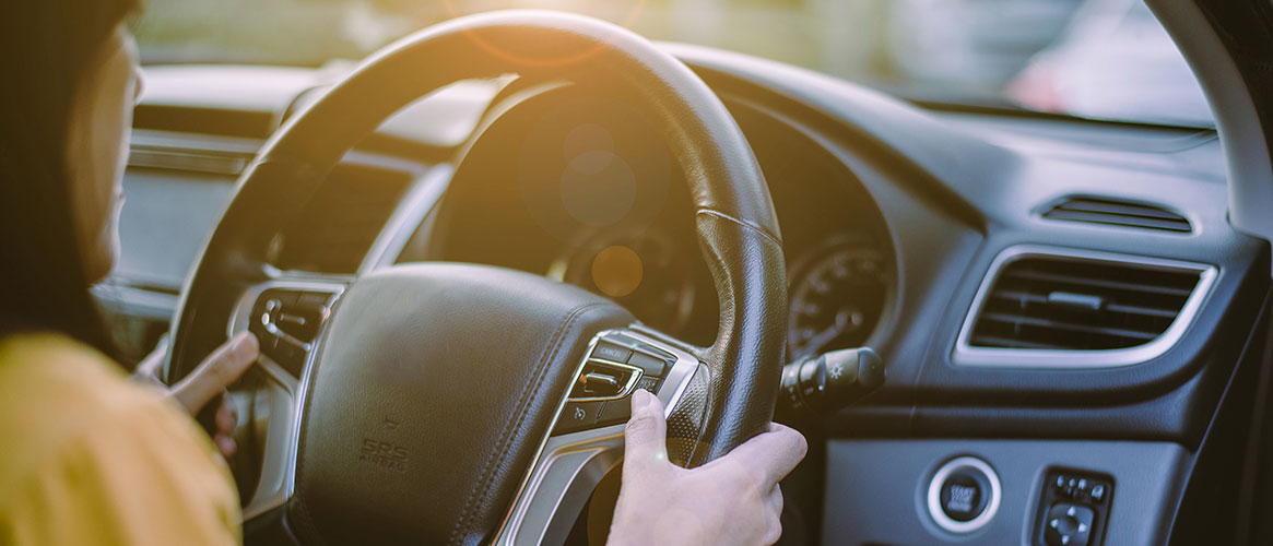 Driver hands holding steering wheel and using cruise control