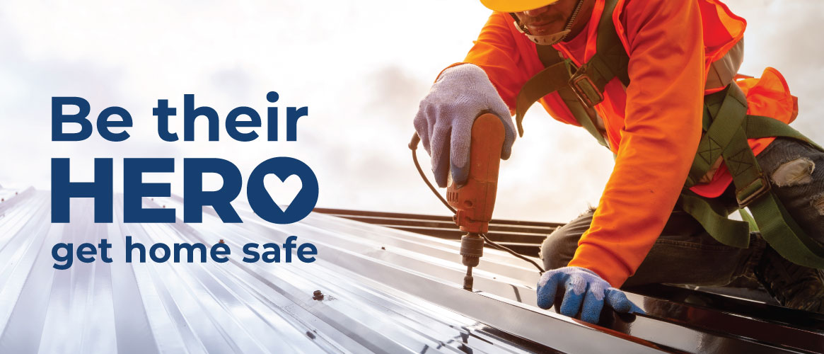 Roof worker wearing fall protection equipment on metal roof next to Be their Hero logo Roof worker wearing fall protection equipment on metal roof next to Be their Hero logo