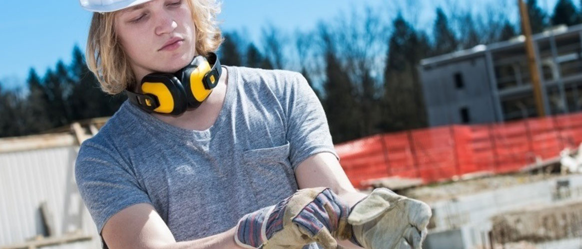 Construction worker protecting her hands from chemicals, dirt, and sharps by putting on gloves